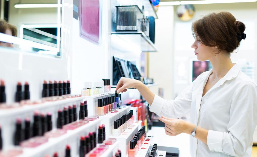 Młoda kobieta ogląda polskie kosmetyki w sklepie.